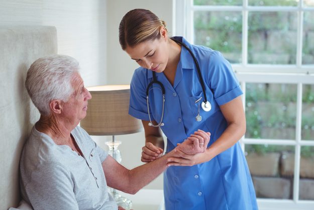 Nurse examining senior man at home