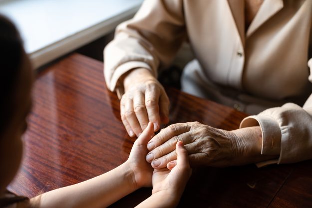 very old woman holding the hands of a child