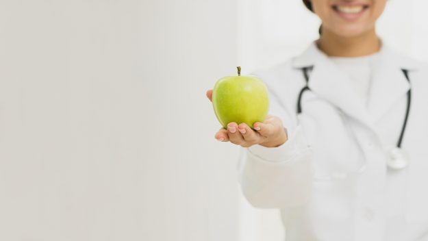 close-up-doctor-holding-up-green-apple
