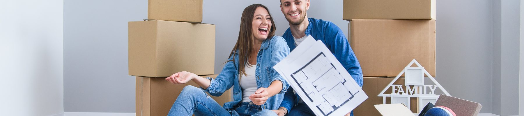 Beautiful happy young woman and her handsome man in love are throwing up sheets with the layout of their new apartment after removing.