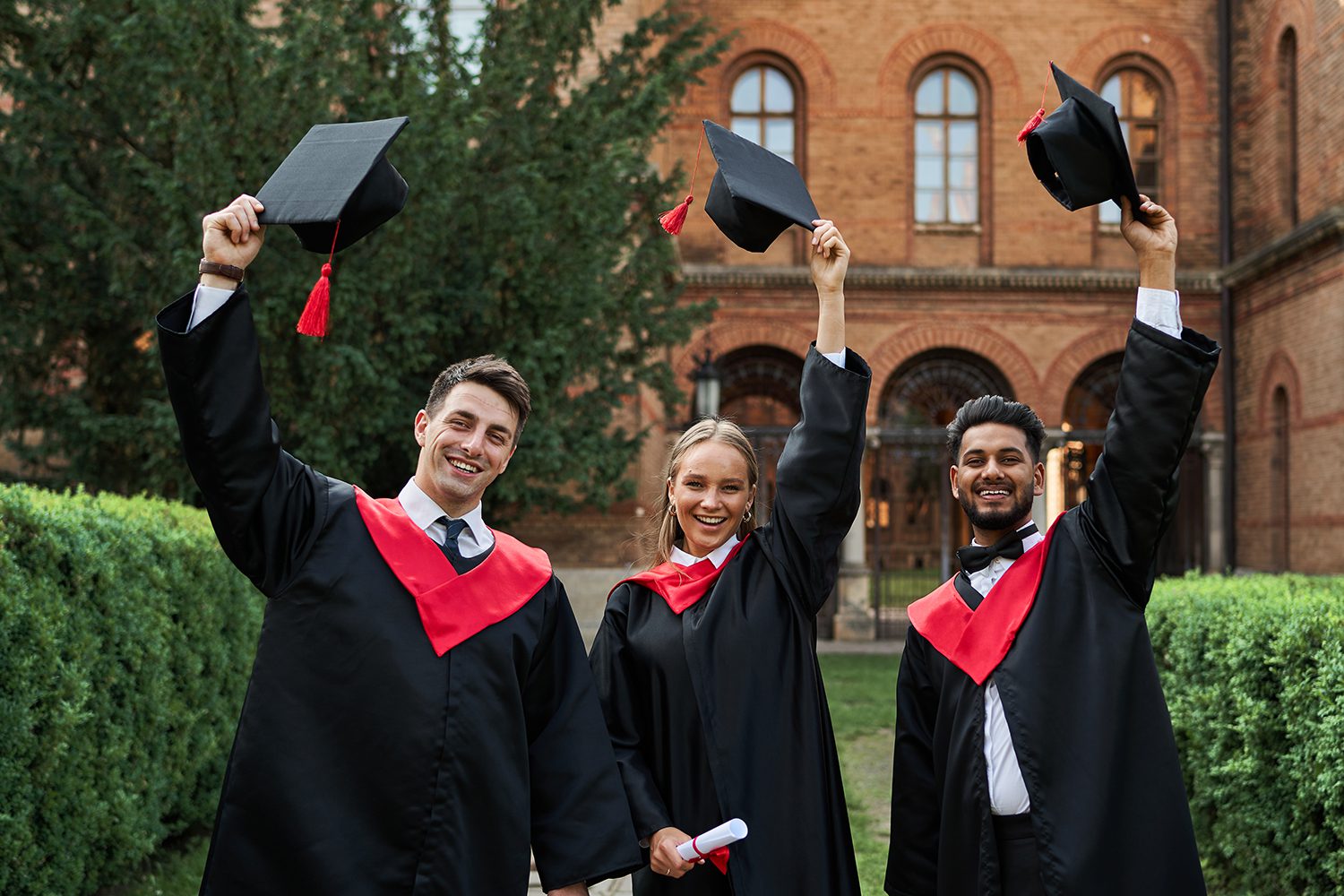 Multinational graduates male and female celebrating graduation i