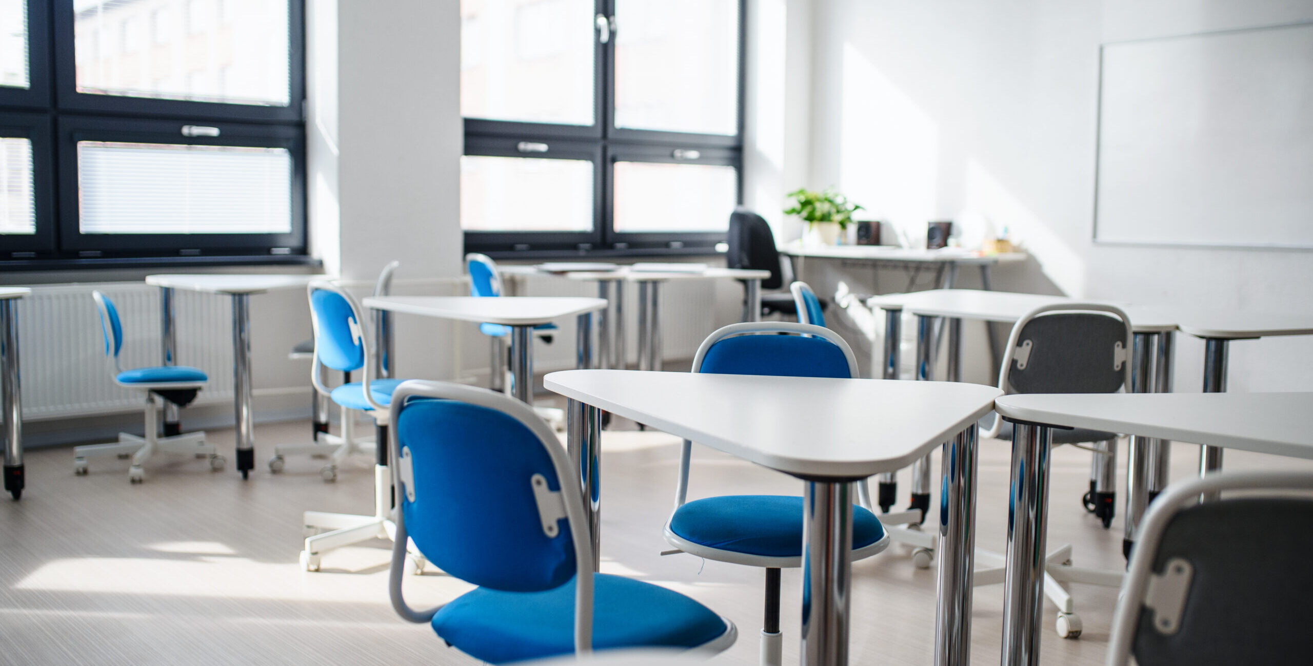 Desks, chairs and whiteboard in empty classroom. Copy space.