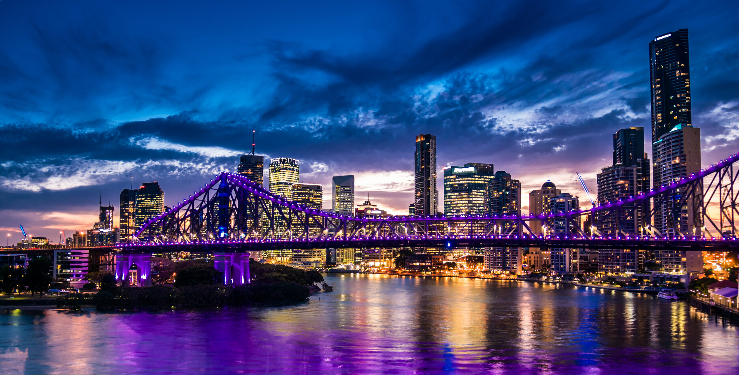 Vibrant night time panorama of Brisbane city with purple lights Vibrant night time panorama of Brisbane city with purple lights on Story Bridge, Australia