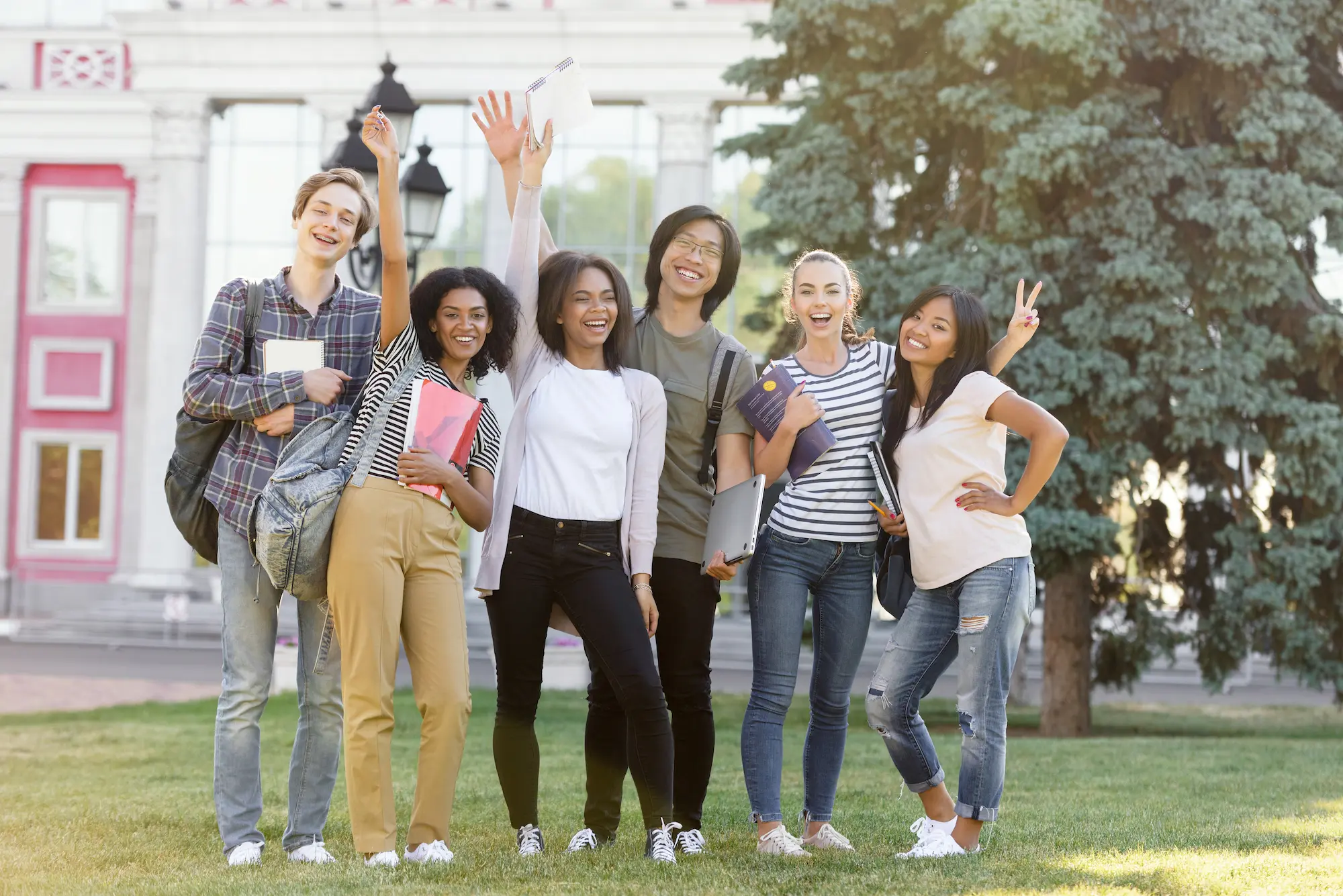 Cheerful students standing and waving outdoors.