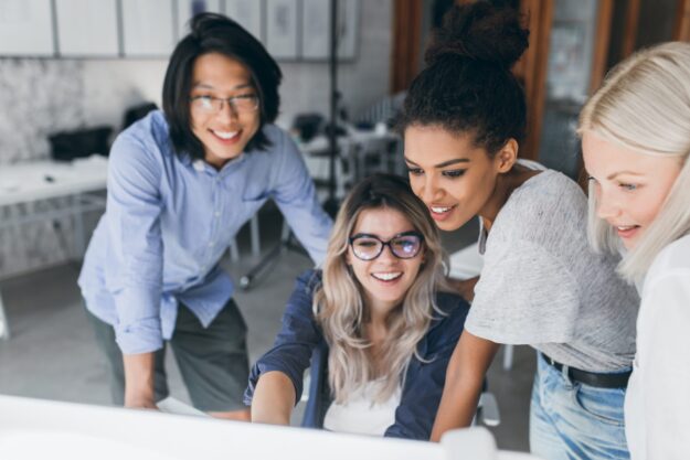 Close-up portrait of freelance it-specialists looking at laptop screen with smile. Asian programmer in glasses helping to mulatto girl in white t-shirt with her project.. Du học ngành Kỹ sư phần mềm Úc – Lộ trình học & định cư rõ ràng