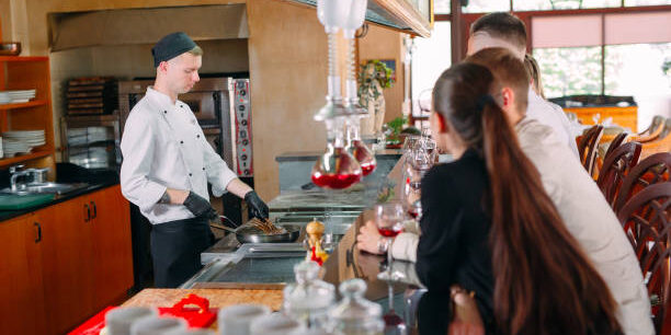 The chef prepares food in front of the visitors in the restaurant.